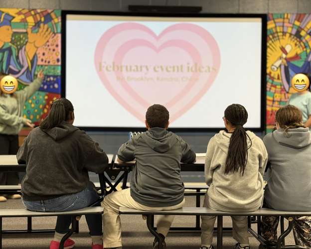 A group of young people watching on as 2 of their peers present on the projected screen