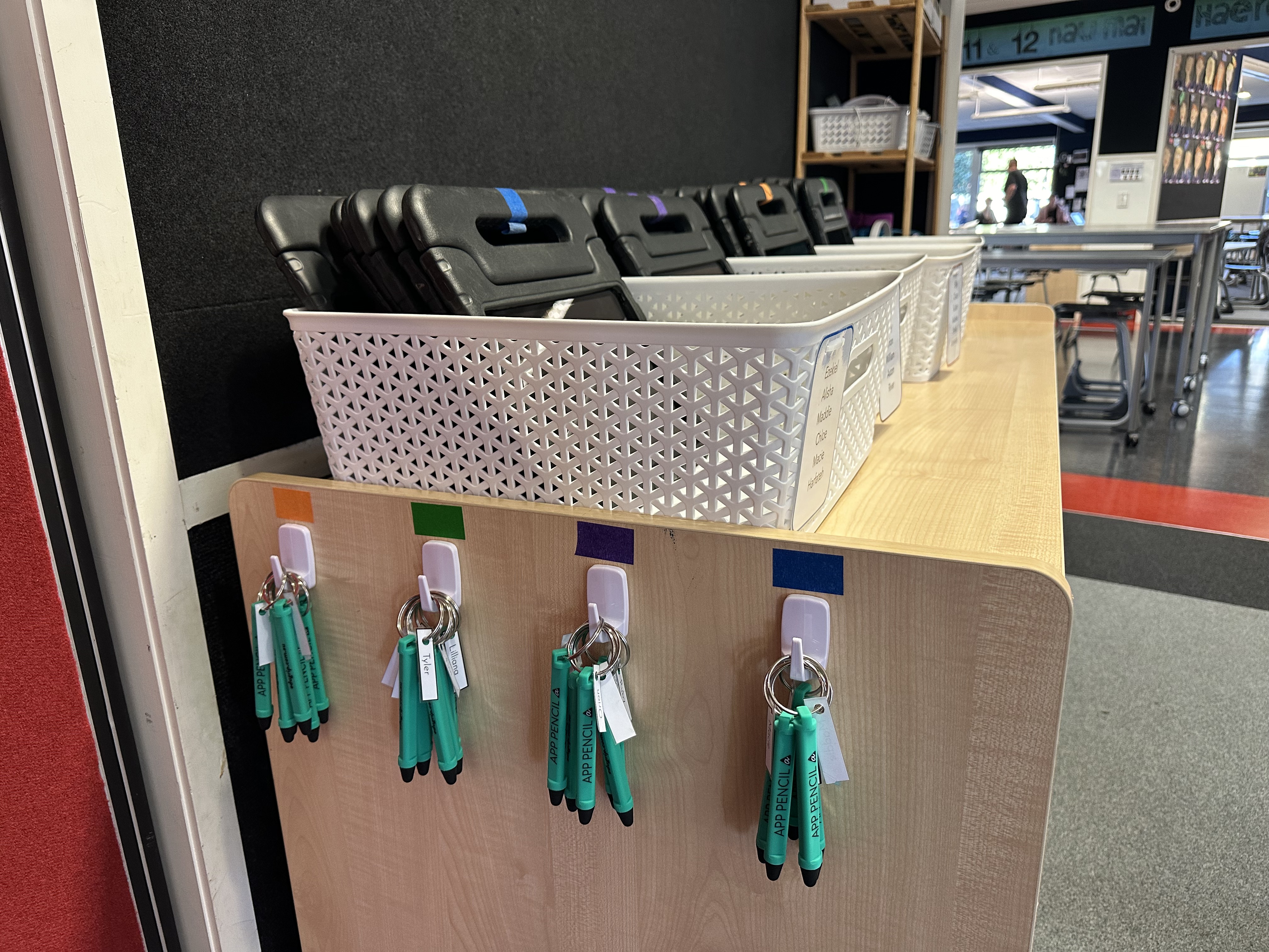 Stylus pencils hanging on coloured hooks for organisation and student accessibility 