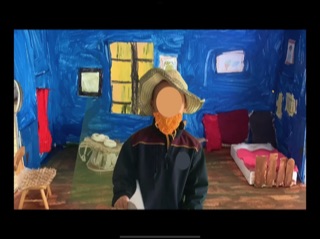 Photo of student using green screen with in diorama of Van Gogh’s bedroom. 