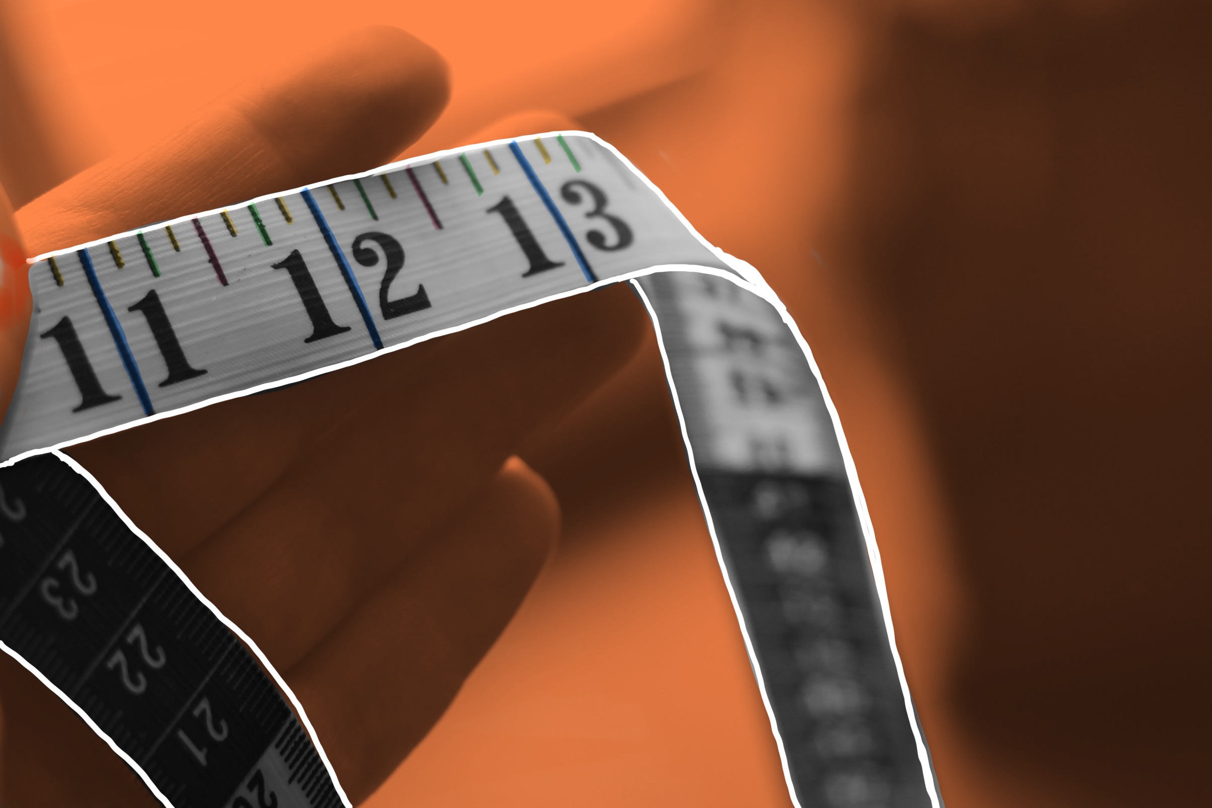A hand holds a tape measure. It stands out against an orange background.