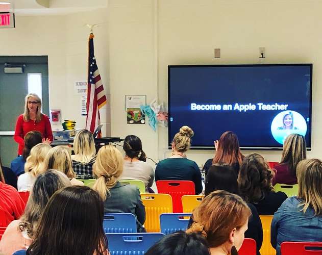 Kristen Brooks in a red shirt leads a professional learning presentation to the staff at Indian Knoll Elementary School.