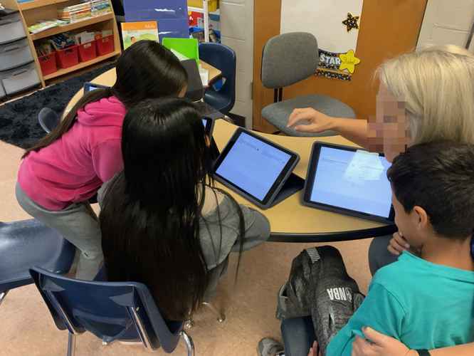 Three students and a teacher use the native translate app on iPad to have a multilingual conversation.