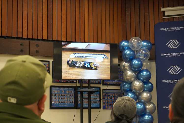 Boys & Girls Club of Silicon Valley staff and finalists' families watch the animations on a television monitor.