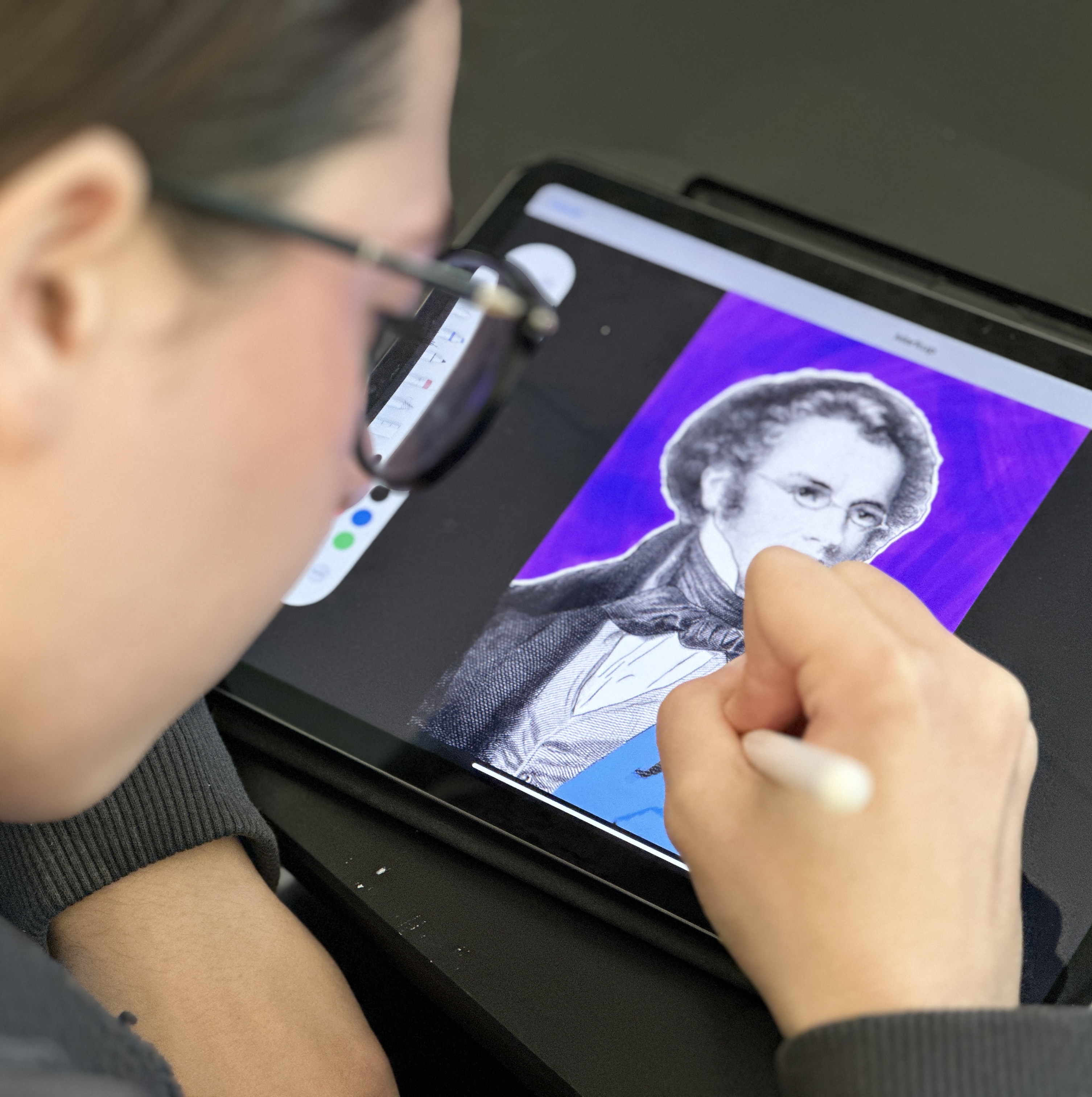 Student coloring an image of Franz Schumann on her iPad.