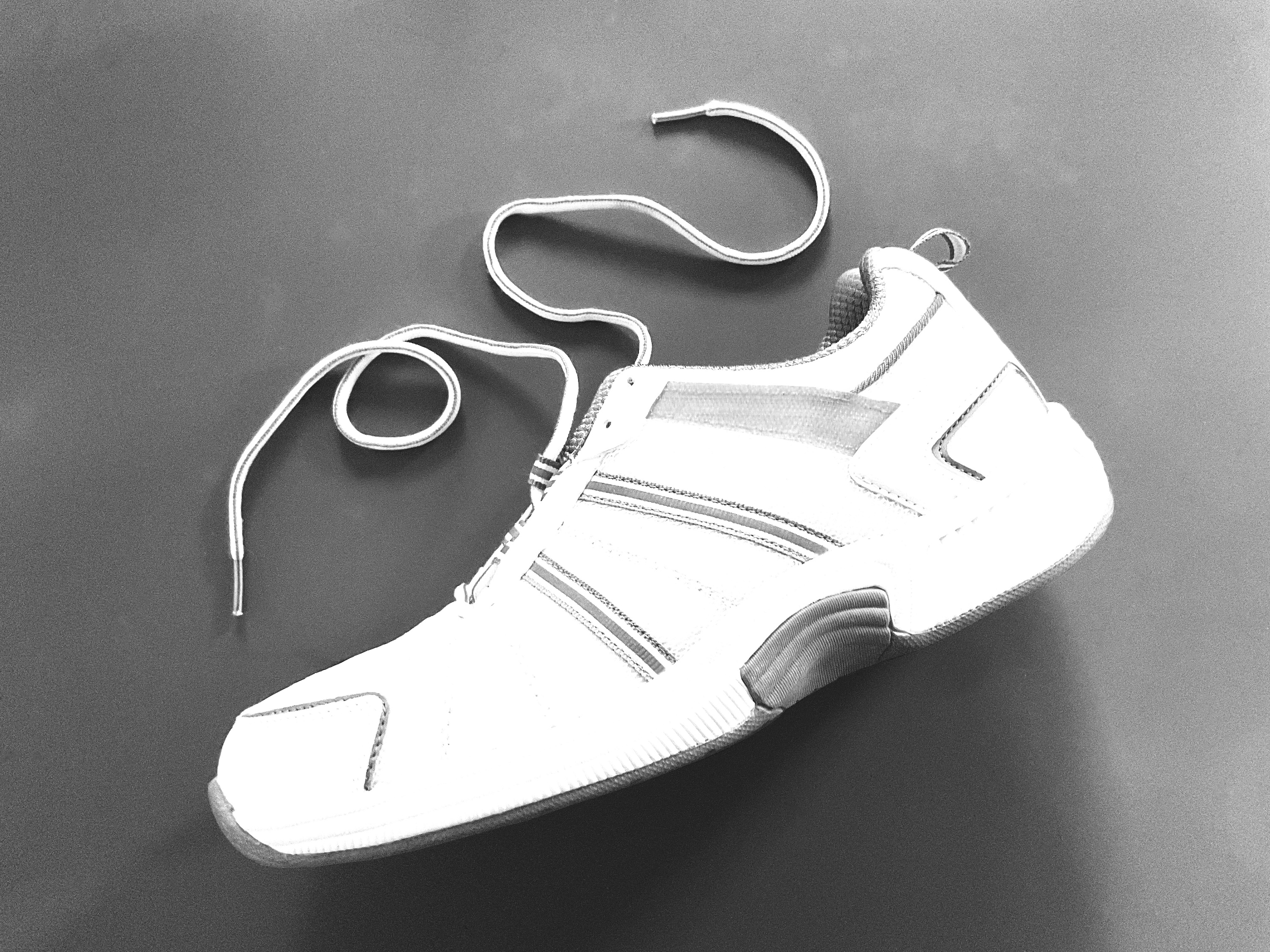 black and white photo of a white athletic shoe against a gray background