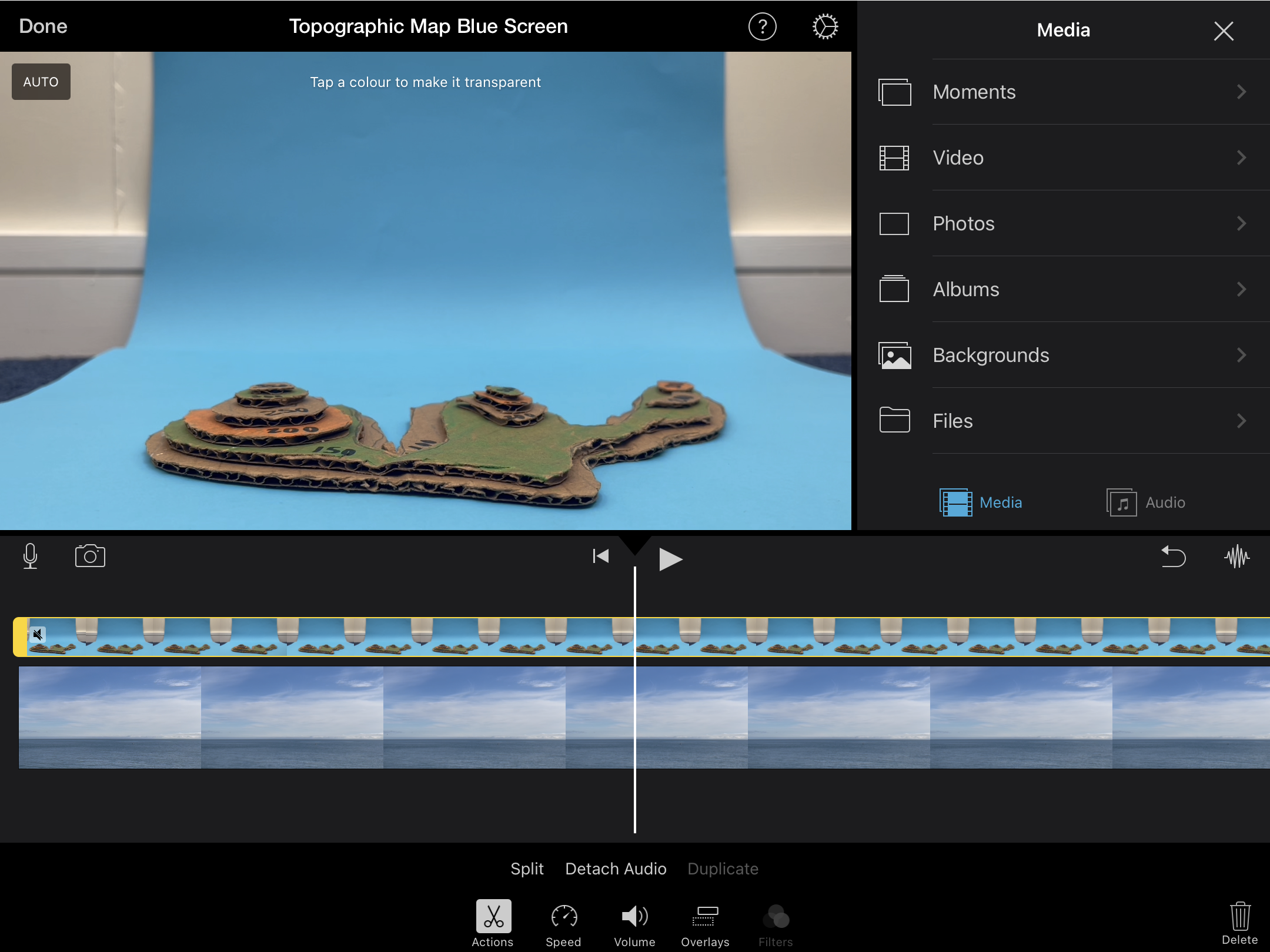 Screenshot from iMovie for iPad. A cardboard topographic map on blue paper has been added to as an overlay image.